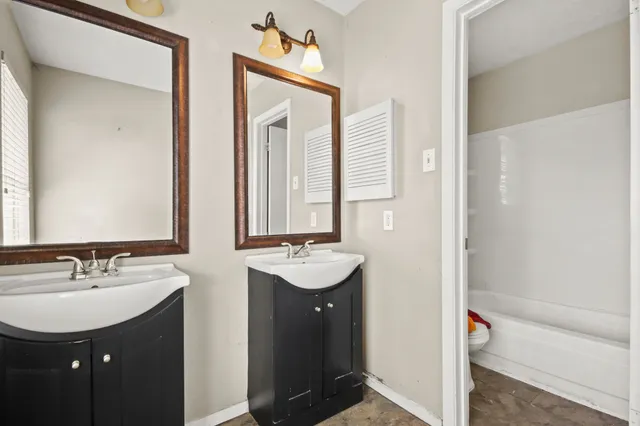 a bathroom with a sink double vanity granite tub and a mirror