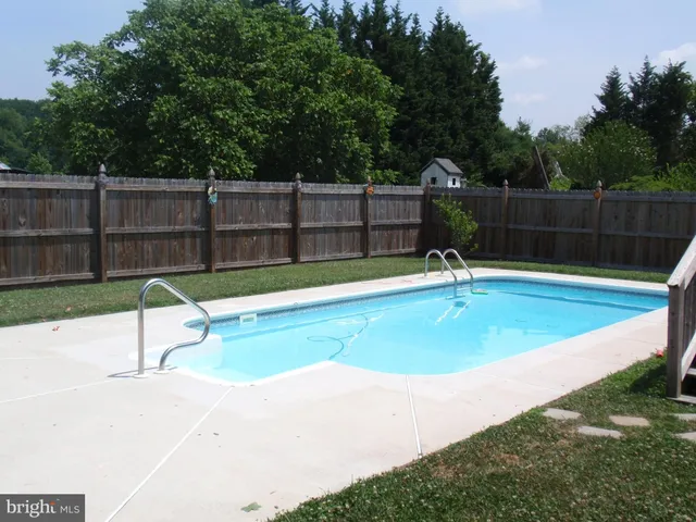 a view of a backyard with a small pool and wooden fence