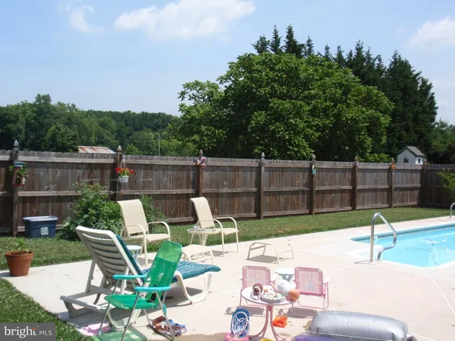 a view of backyard with seating space and trees in the background