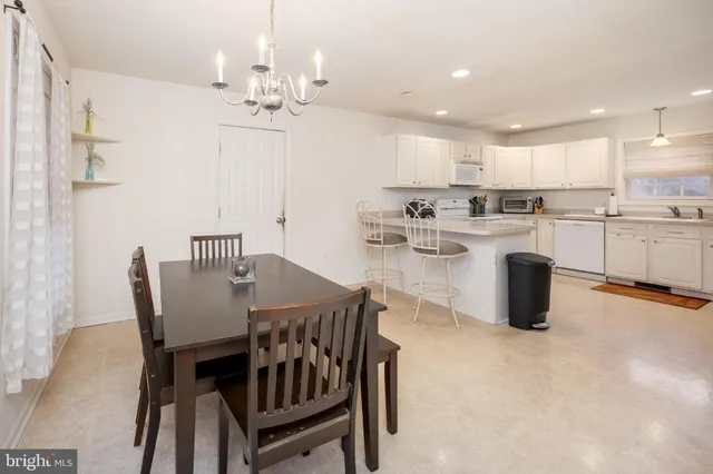 a kitchen with kitchen island a dining table chairs stainless steel appliances and cabinets