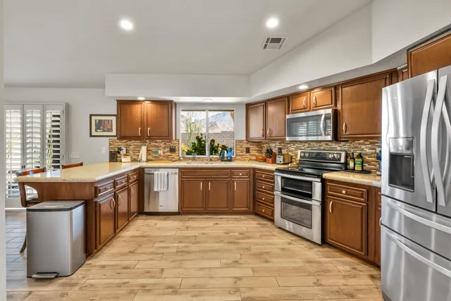 a kitchen with stainless steel appliances granite countertop a stove top oven a sink dishwasher a refrigerator and a refrigerator