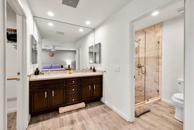 a spacious bathroom with a double vanity sink a toilet and shower