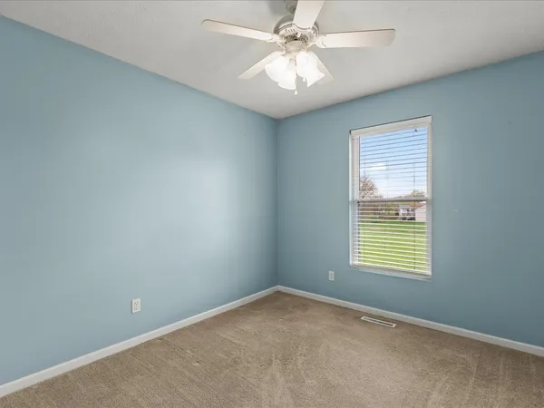 an empty room with a window and a fan