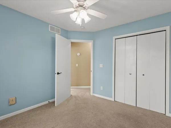 a view of an empty room and chandelier fan