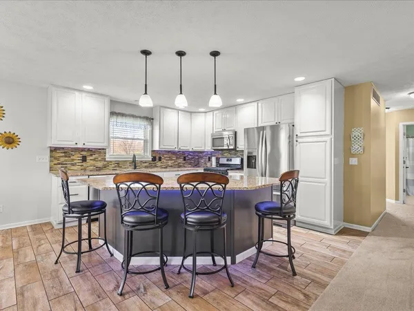 a kitchen with granite countertop a dining table chairs and a refrigerator