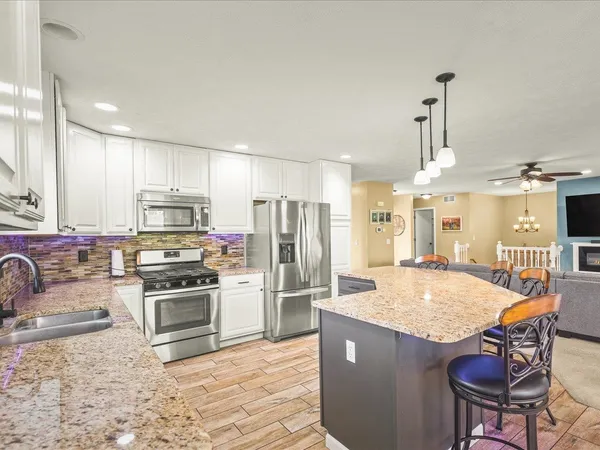 a kitchen with granite countertop a stove refrigerator and microwave