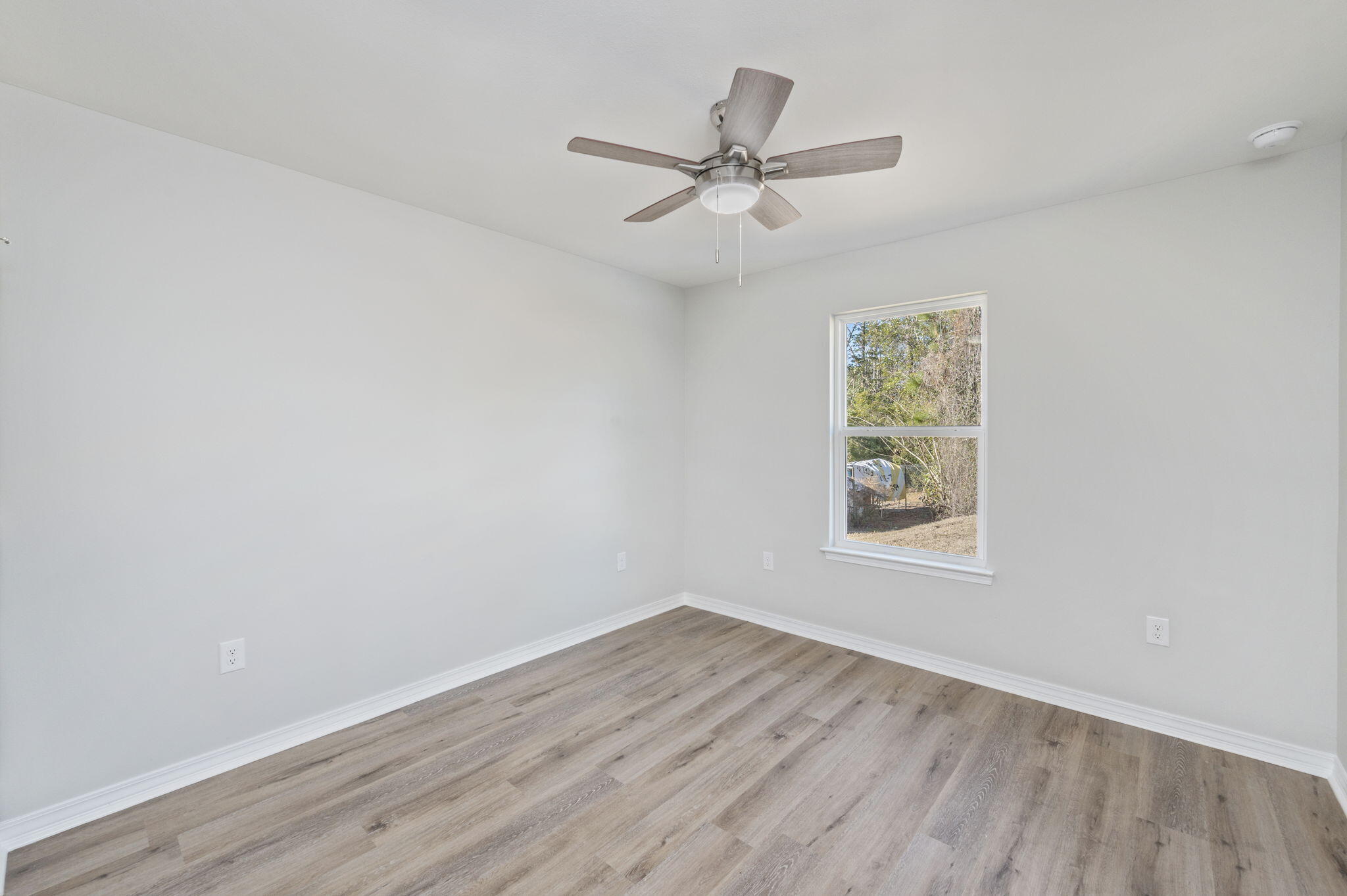 1206 Sunshine Drive Crestview, FL 32539 - Photo 19 of 28 an empty room with wooden floor fan and windows