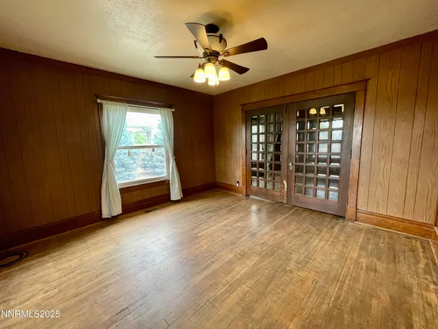 an empty room with wooden floor chandelier and windows