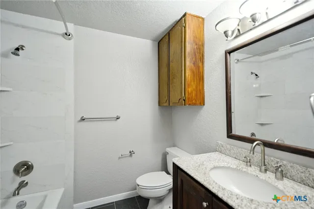 a bathroom with a granite countertop sink a toilet and a mirror