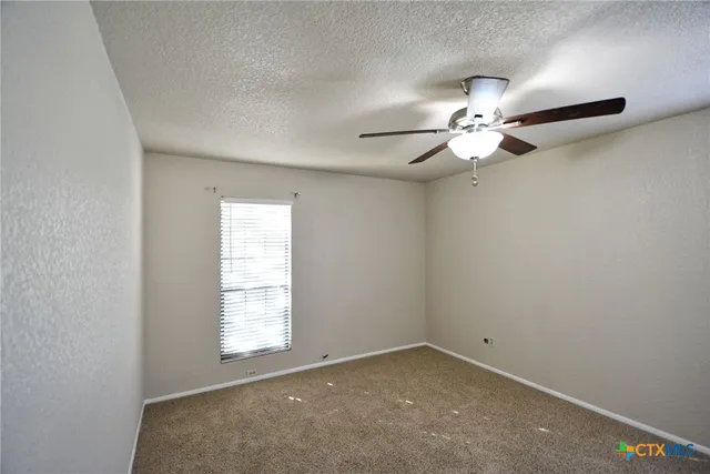 an empty room with a window and a ceiling fan