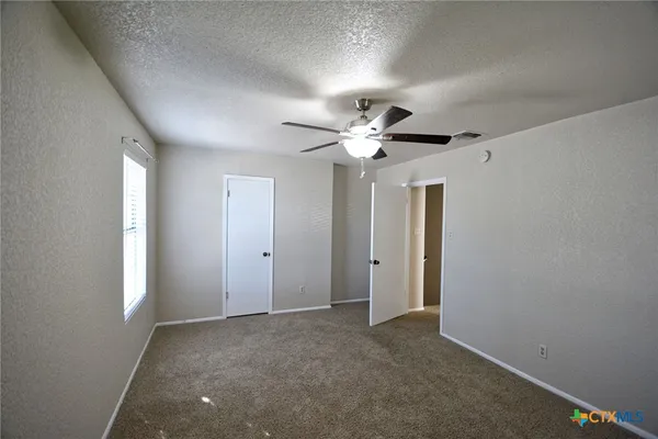 an empty room with a chandelier fan and windows