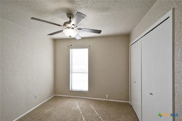 an empty room with windows and fan