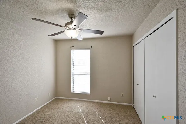 an empty room with windows and fan