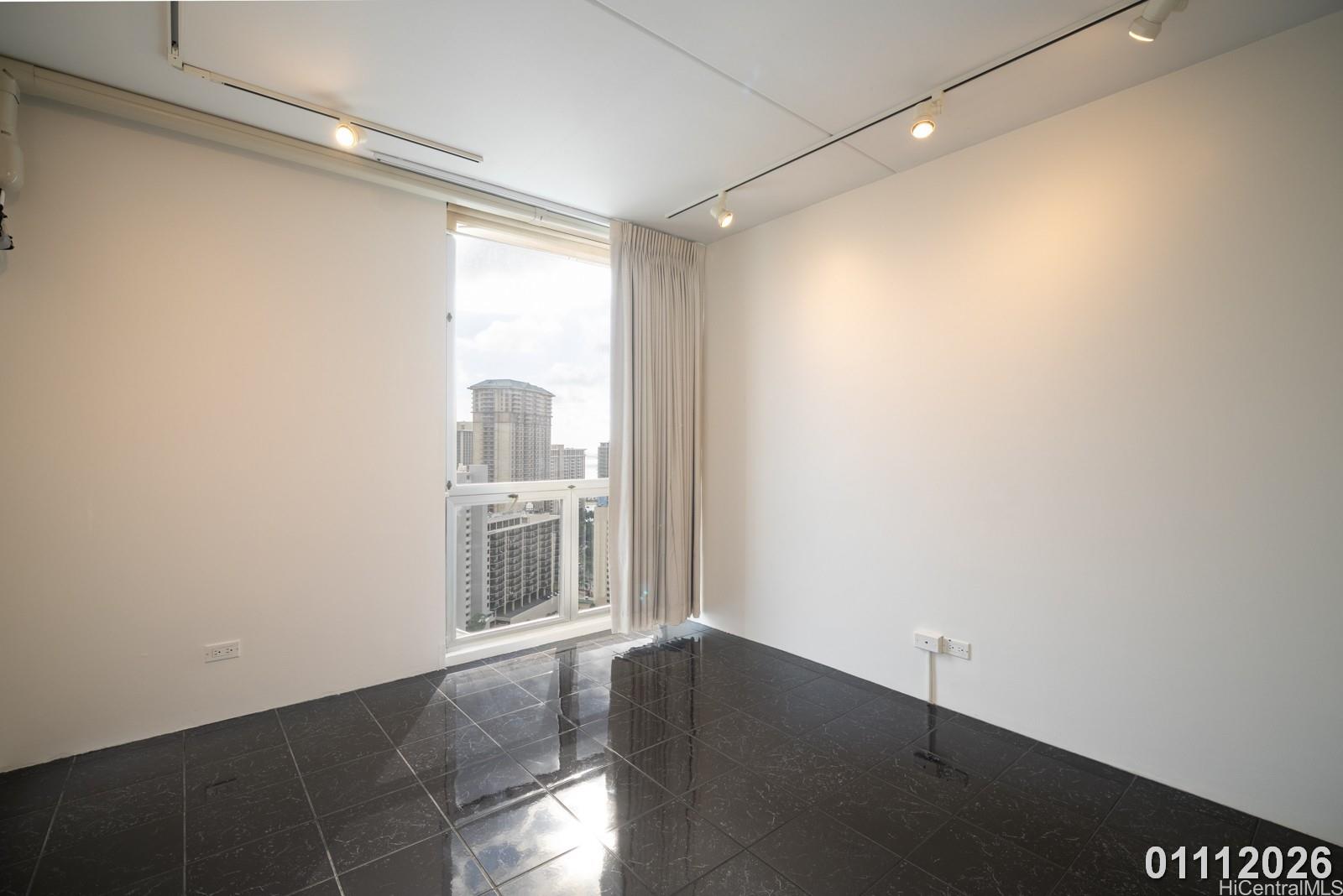 469 Ena Road, Unit 2903 Honolulu, HI 96815 - Photo 14 of 25 a view of an empty room with wooden floor and a window