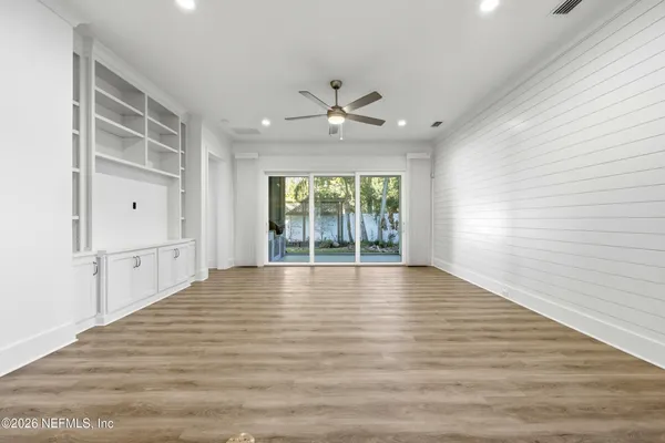 a view of an empty room with a window and wooden floor