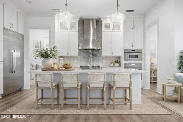 a white kitchen with granite countertop a table and chairs in it
