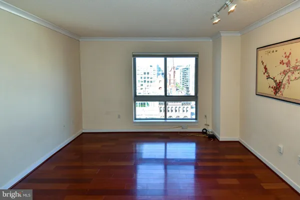 a view of an empty room with wooden floor and a window
