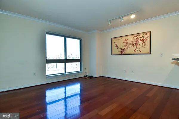 a view of an empty room with wooden floor and a window