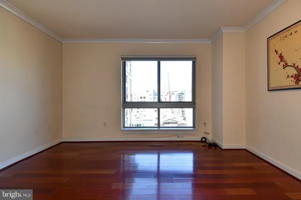 a view of an empty room with wooden floor and a window