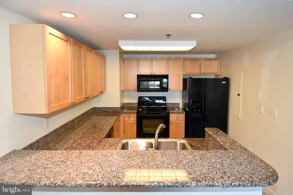 a kitchen with stainless steel appliances granite countertop a refrigerator a stove and a sink