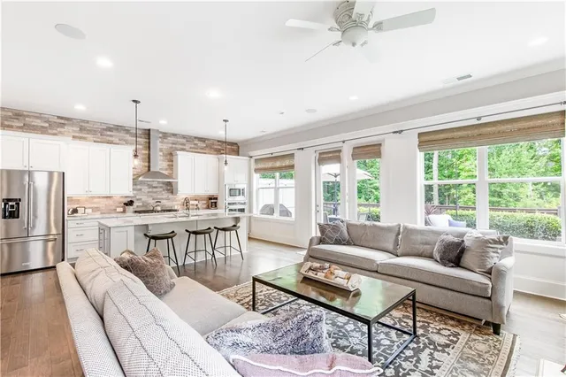 a living room with furniture kitchen view and a large window