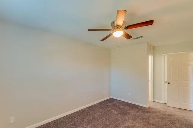 an empty room with closet and chandelier fan