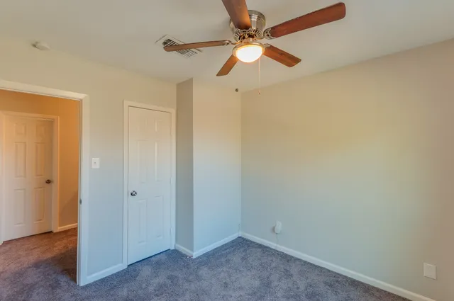 an empty room with a fan & a ceiling fan