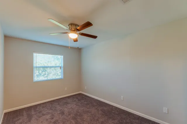 an empty room with a window and a fan