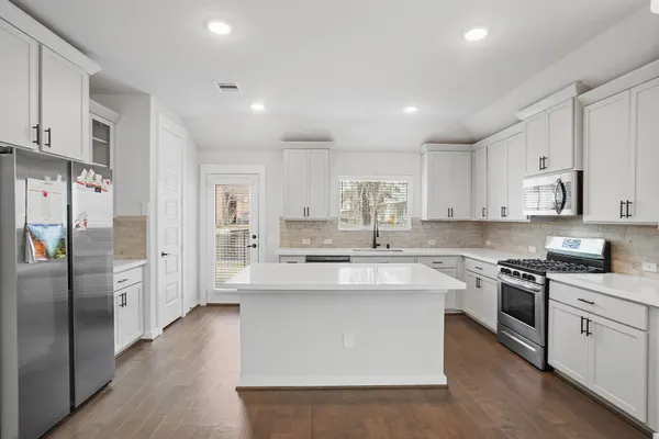 a large kitchen with stainless steel appliances lots of white cabinets
