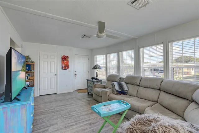 a living room with furniture a ceiling fan and a flat screen tv