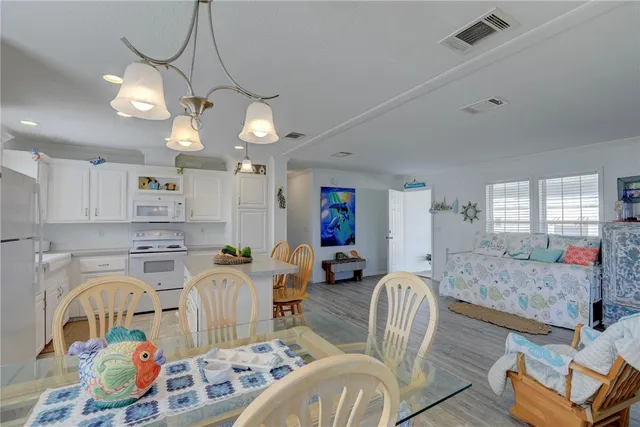 a living room with furniture kitchen view and a chandelier