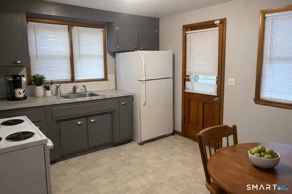 a kitchen with stainless steel appliances granite countertop a refrigerator a stove a sink and a dining table with the view of bathroom