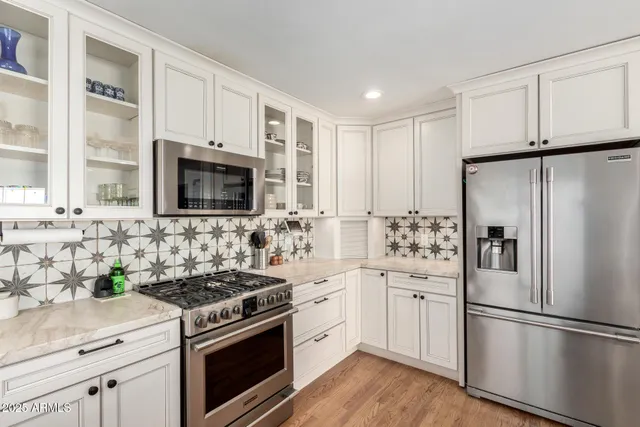 a kitchen with cabinets stainless steel appliances and wooden floor
