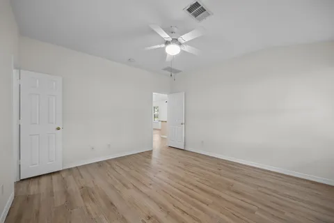 an empty room with wooden floor and fan