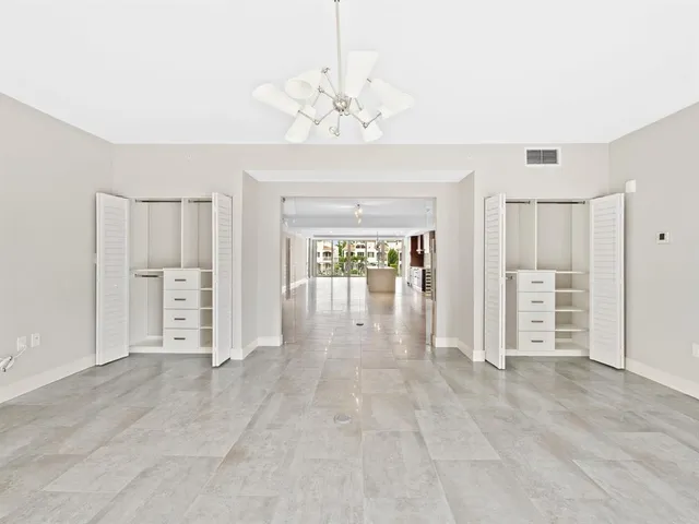 an empty room with chandelier fan and windows