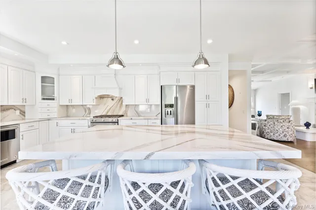 a large kitchen with kitchen island white cabinets and stainless steel appliances