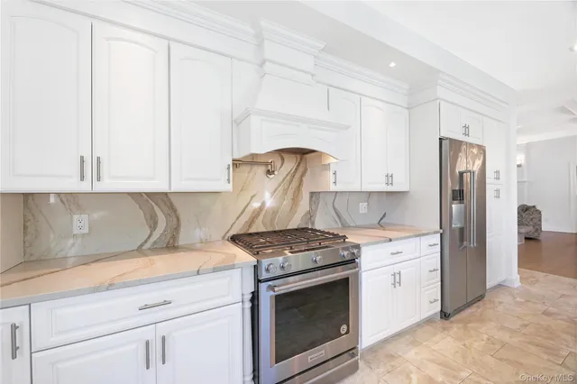 a kitchen with stainless steel appliances granite countertop a stove a refrigerator and a white cabinets