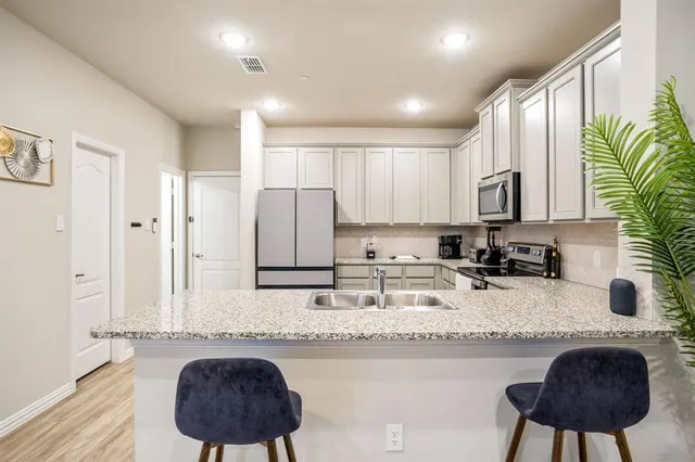 a kitchen with stainless steel appliances granite countertop a sink a stove a refrigerator a counter space and cabinets