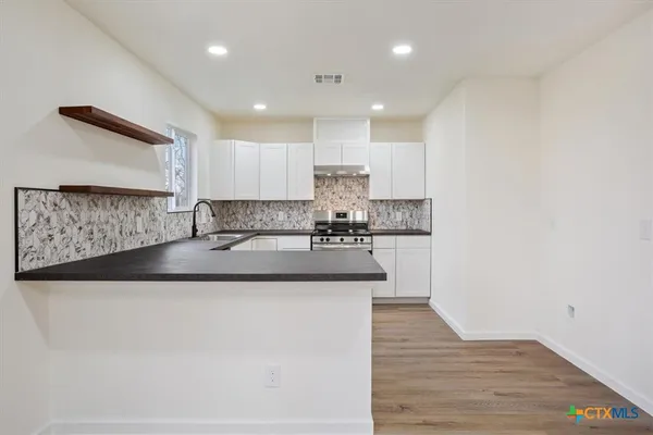 a kitchen with kitchen island granite countertop wooden cabinets and a sink