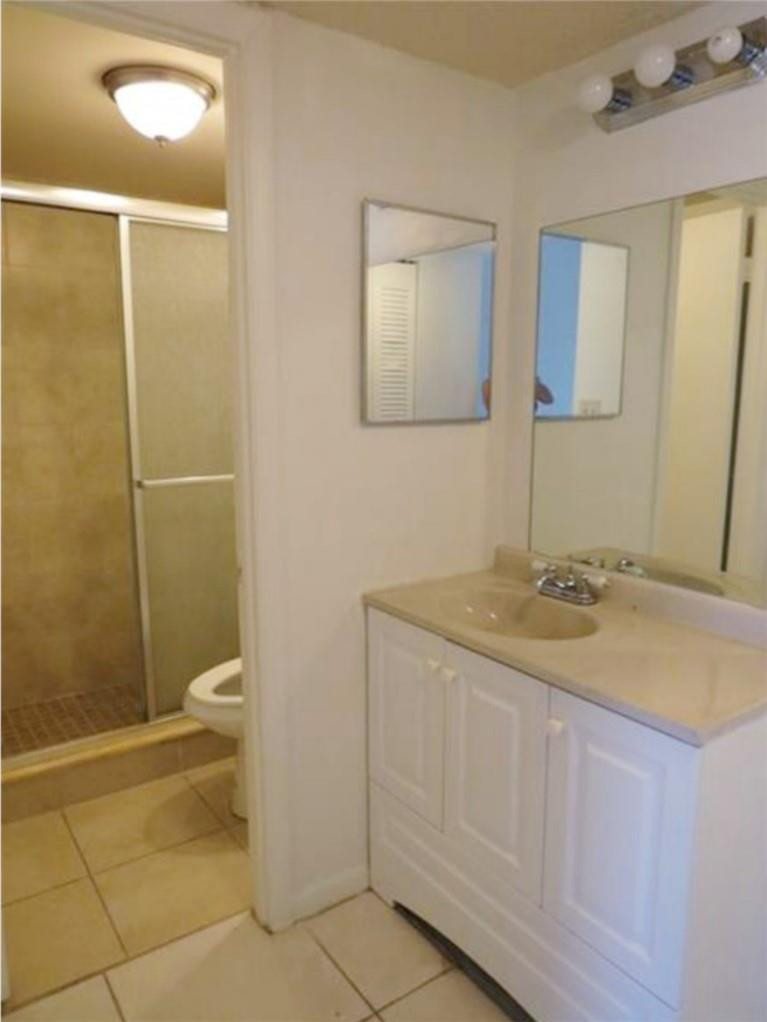 8401 West Sample Road, Unit 21 Coral Springs, FL 33065 - Photo 5 of 6 a bathroom with a granite countertop sink and a mirror