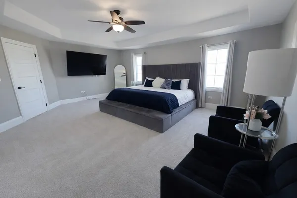 a spacious bedroom with a bed chandelier and a window