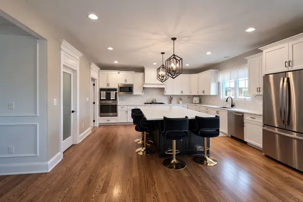 a large kitchen with stainless steel appliances a dining table chairs and wooden floor