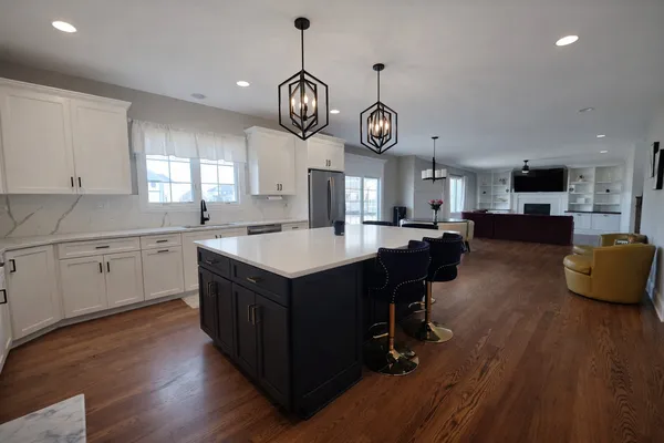 a kitchen with a large center island white cabinets stainless steel appliances and wooden floor