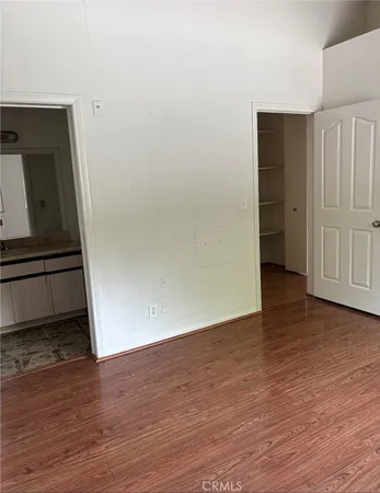 a view of an empty room with wooden floor and closet