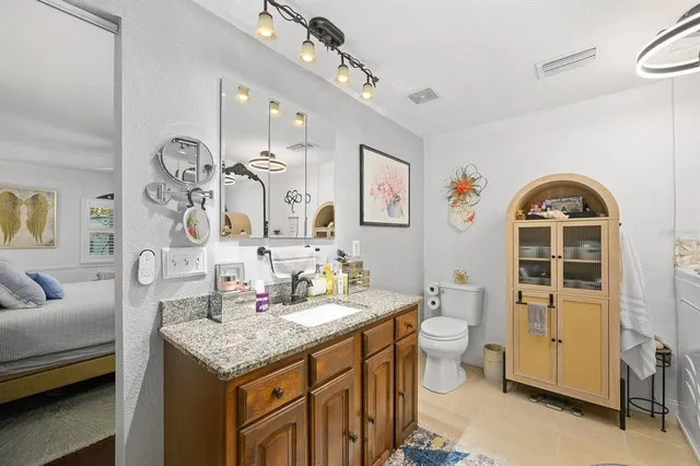 a spacious bathroom with a granite countertop sink a toilet and a mirror