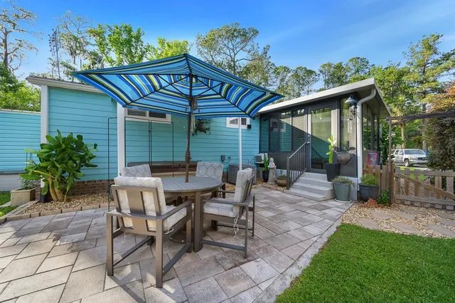 a view of a patio with table and chairs potted plants and large tree