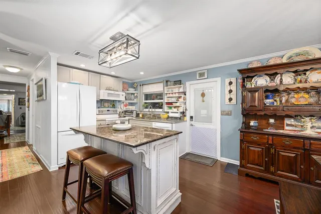 a kitchen with stainless steel appliances granite countertop a table chairs and a refrigerator