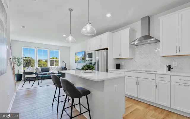 a kitchen with stainless steel appliances a dining table chairs stove and white cabinets
