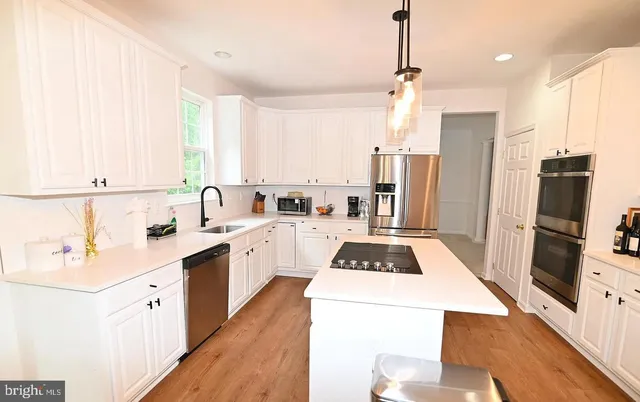 a kitchen with a sink a counter top space stainless steel appliances a window and a refrigerator