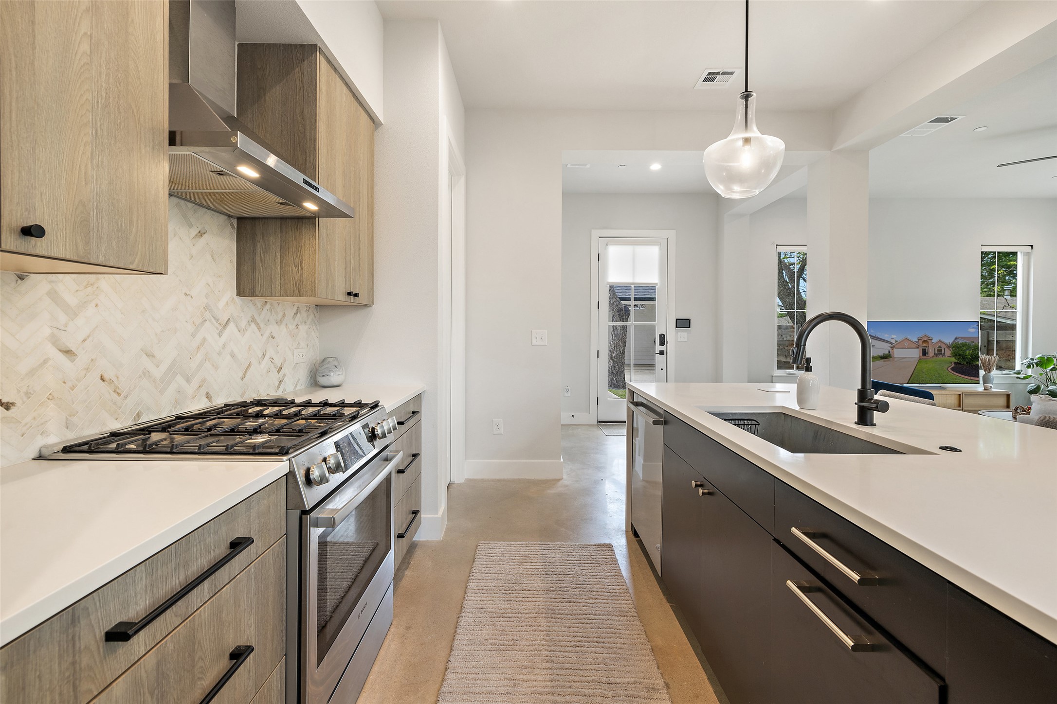 1504 Ruth Avenue, Unit 3 Austin, TX 78757 - Photo 15 of 39 A contemporary kitchen boasts a gas range, white countertops, and a striking dark island with a built-in sink.